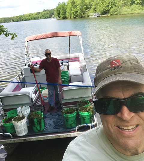 boat carrying buckets of curly-leaf pondweed (CLP) that Greg and Keith pulled from the Lake June 5, 2022